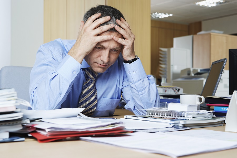 businessman sitting at desk with head in hands